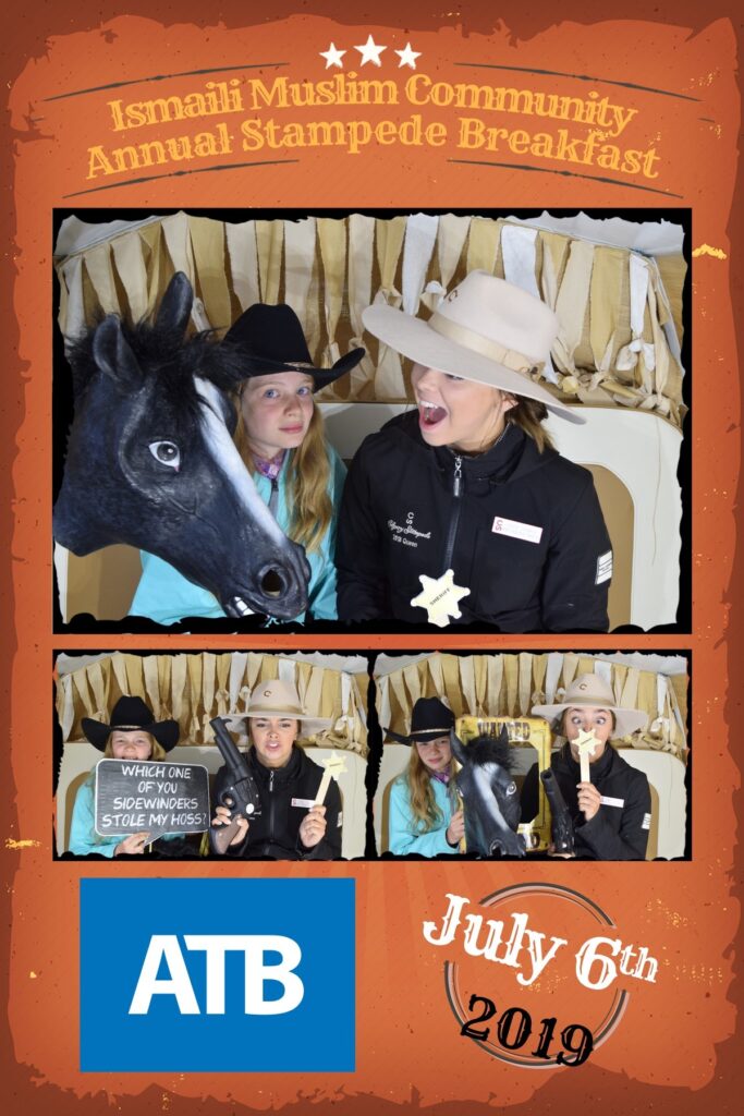 Calgary Stampede photo booth rental setup by Hip Image for the Ismaili Muslim Community Annual Stampede Breakfast on July 6th, 2019, featuring a "WHICH ONE OF YOU SIDEWINDERS STOLE MY HOSS" sign, the ATB logo, and the text "Ismaili Muslim Community Annual Stampede Breakfast."